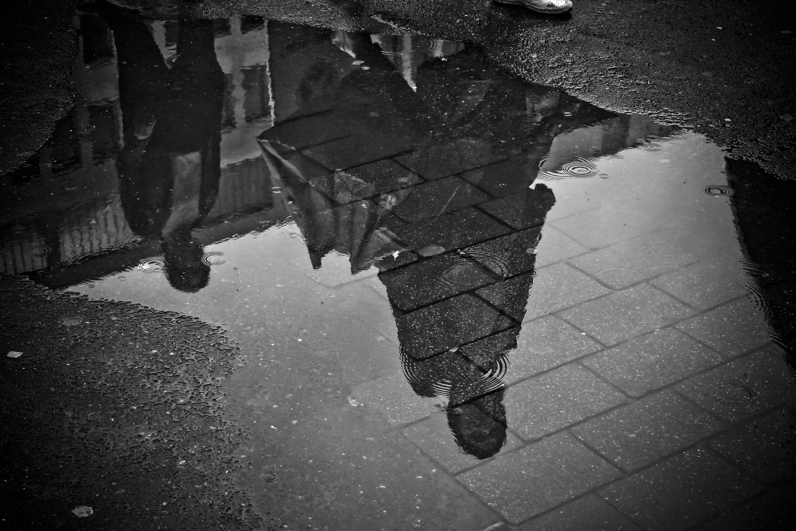 Rain puddle reflecting the sky, illustrating the effects of seasonal weather on asphalt and concrete pavement durability and water drainage.