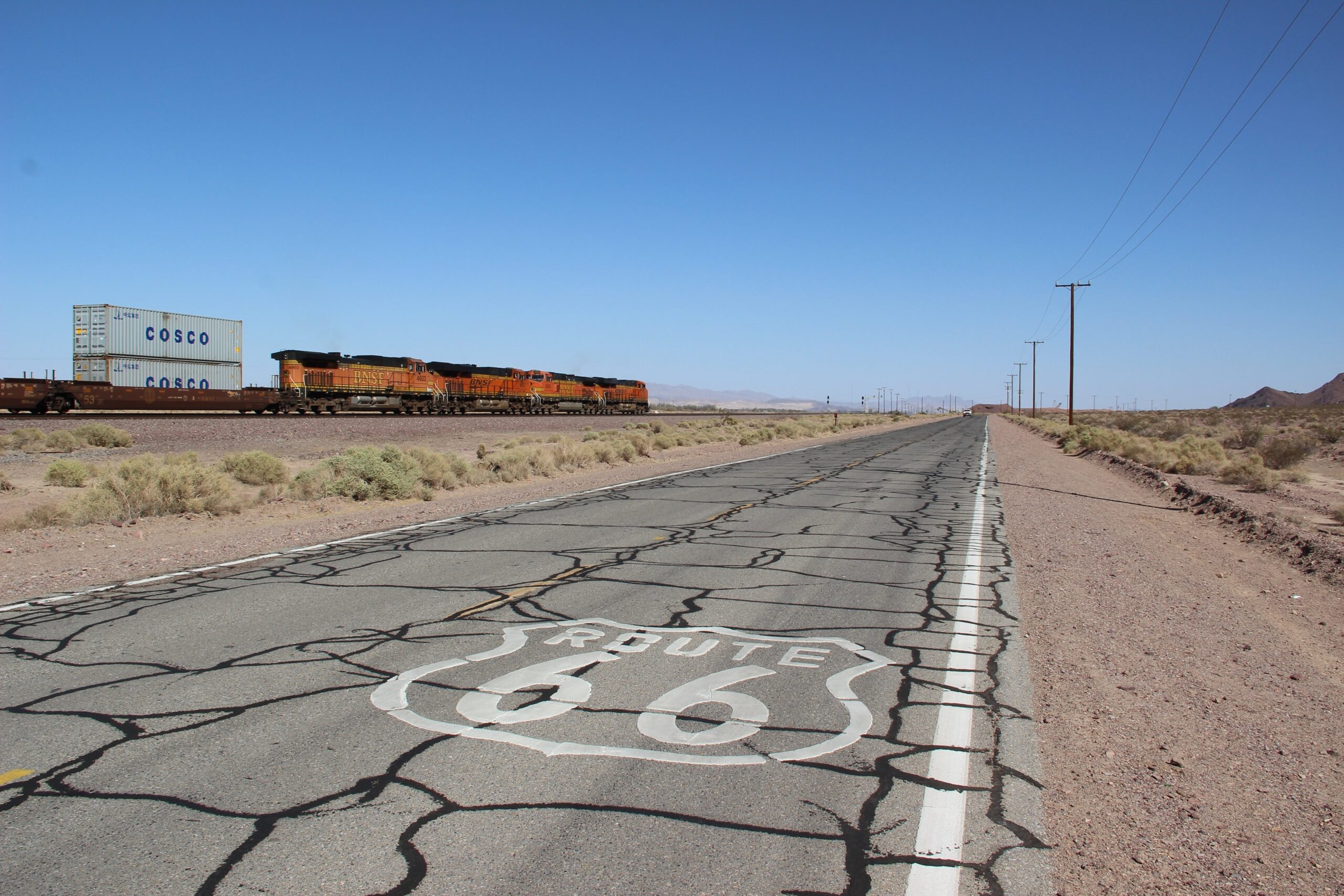 Historic Route 66 asphalt road with train tracks, symbolizing durable pavement and long-lasting road infrastructure.